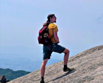 A student traverses a large rock.