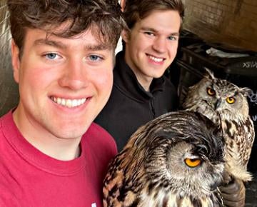 Students smile while holding owls.
