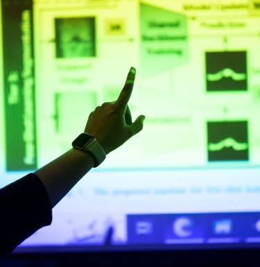 Hand pointing at research on a screen at a presentation.