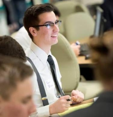 Male student wearing glasses listens in the classroom