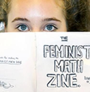 Woman holding up paper that says "Feminist Math Zone"