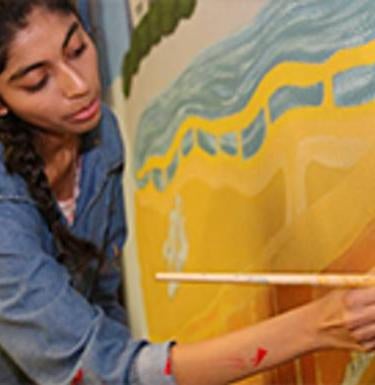Creative Arts Fellowship student paints a mural.