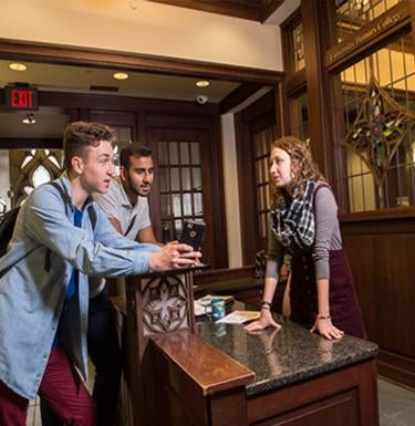 Three students share a conversation in the Honors College lobby