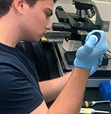 Research fellow pipettes in the lab.