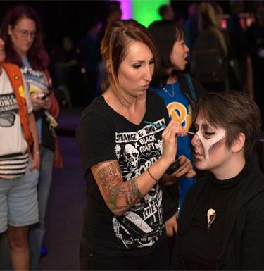 An artist puts makeup on an attendee at a Pitt Romero event.