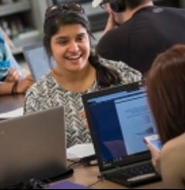 Students work in a room with laptops and bookcases