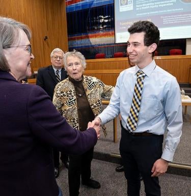 Zachary Miller shaking hands with Mary Crossley.