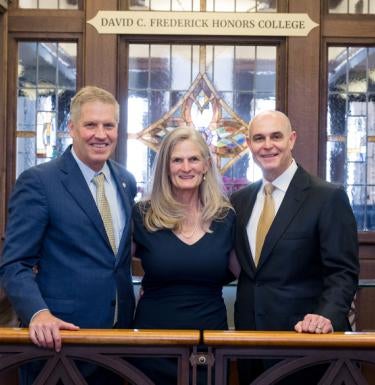 Chancellor Patrick Gallagher (left), Sophie Lynn (center), and David C. Frederick (right) stand before the Frederick Honors College's new sign.