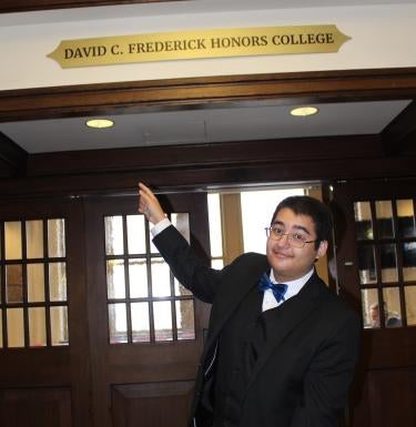 Raja Krishnaswamy pointing to David C. Frederick sign on 35th floor of the Cathedral of Learning.