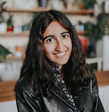Vidya Surti smiling in front of bookshelves