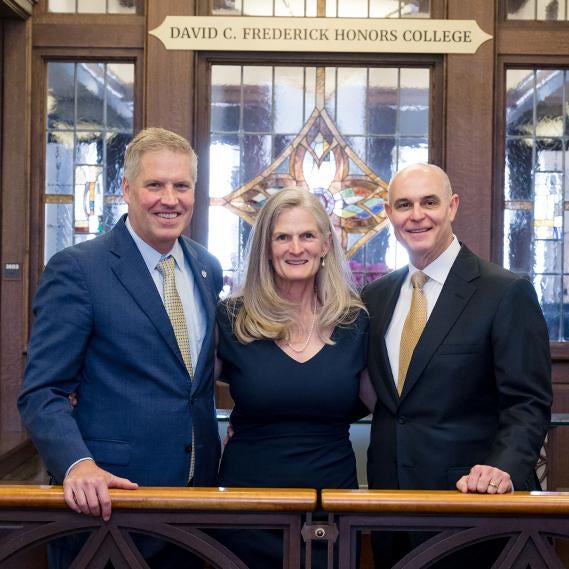 Chancellor Patrick Gallagher (left), Sophie Lynn (center), and David C. Frederick (right) stand before the Frederick Honors College's new sign.